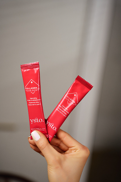 Dziewczyna trzyma w dłoniach dwie saszetki kolagenu Ysto Collagen Your Skin.